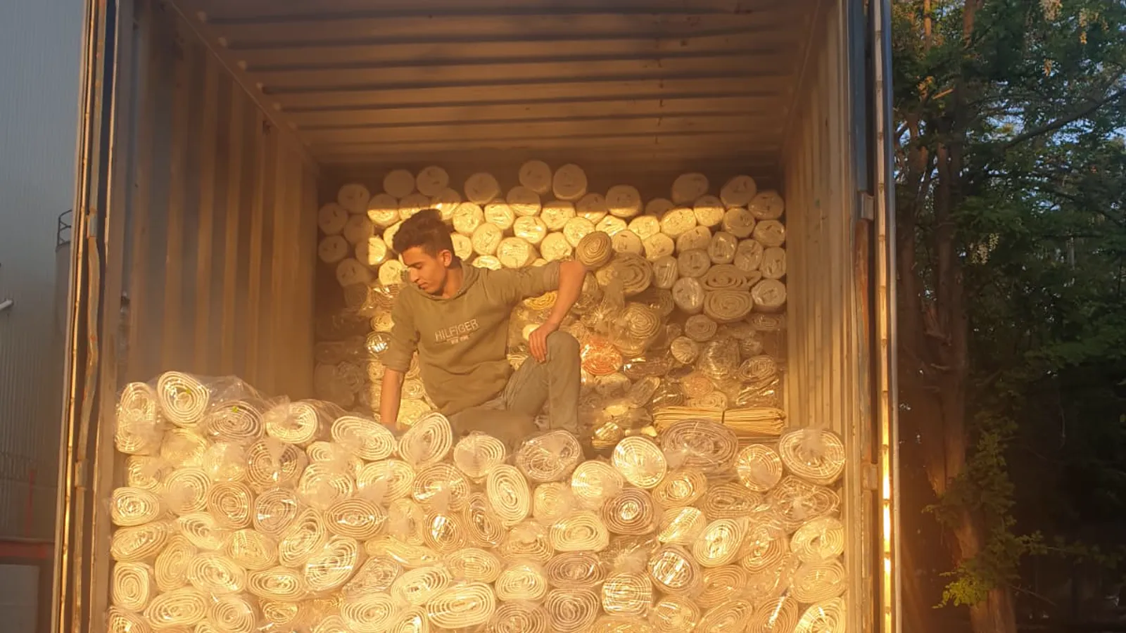A container loaded with rolled Turkish carpets, photographed at golden hour